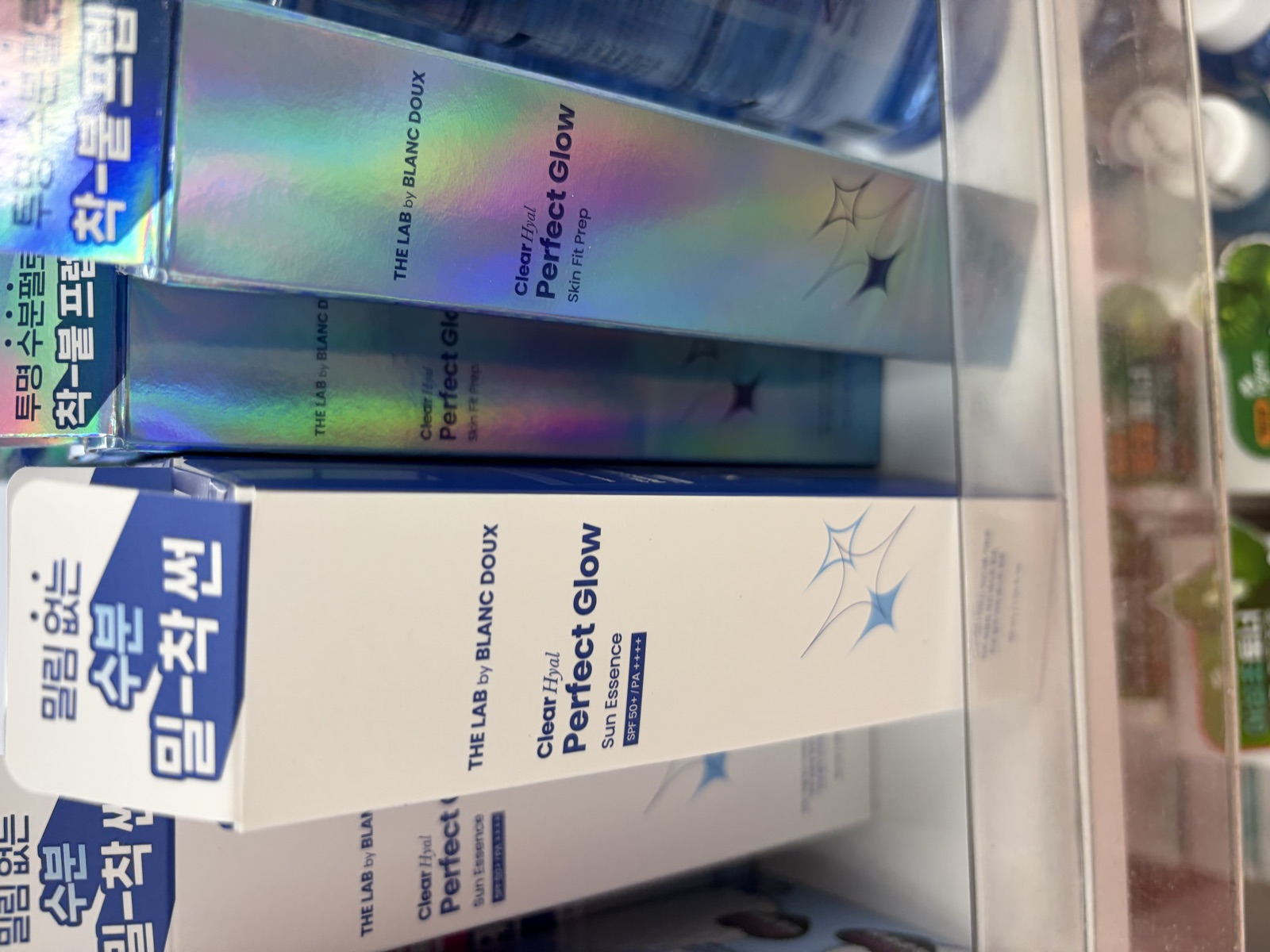 The Lab by Blanc Doux Clear Hyal Perfect Glow Sun Essence box in blue and white on a Daiso shelf showing SPF 50 plus PA four plus rating below the Perfect Glow logo