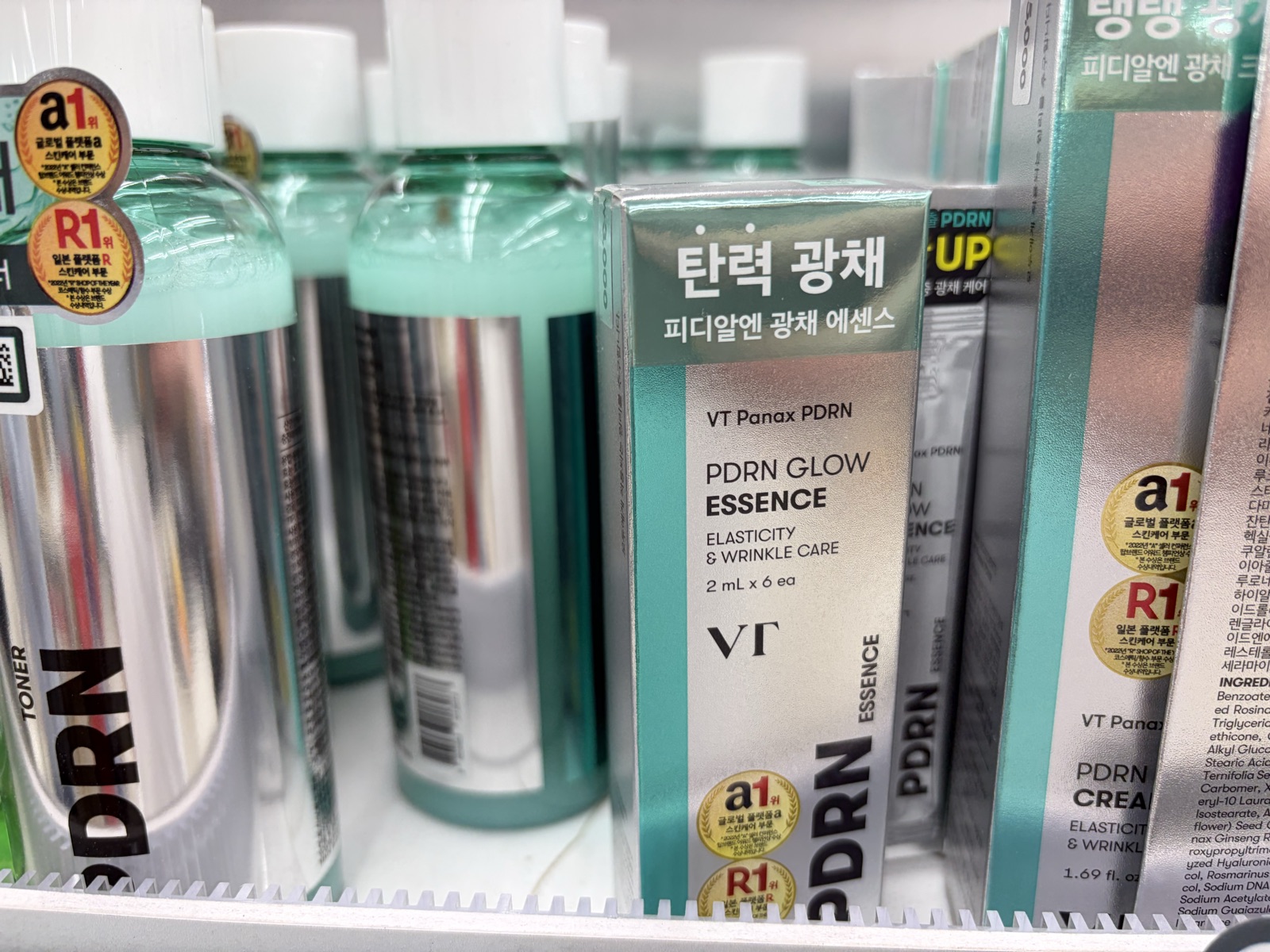 VT Panax PDRN Glow Essence box of six 2ml ampoules on a Daiso shelf beside PDRN toner and cream, labeled elasticity and radiance in Korean