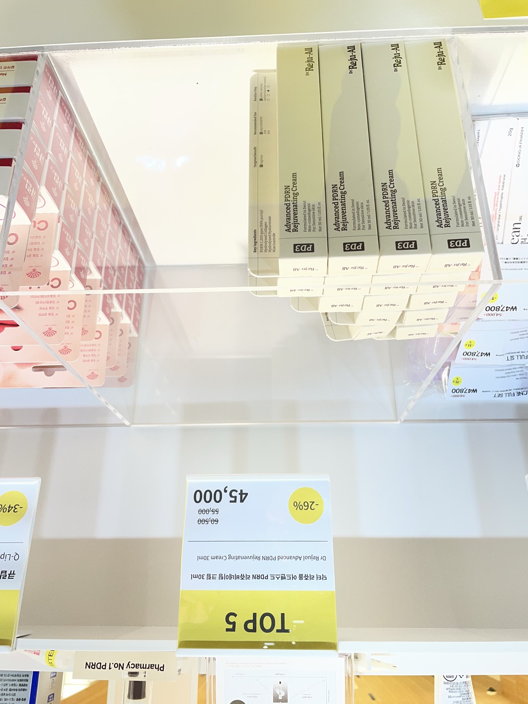 Dr. Reju-All PD3 Advanced PDRN Rejuvenating Cream stacked on a Korean pharmacy shelf with a TOP 5 ranking sign showing a discounted price