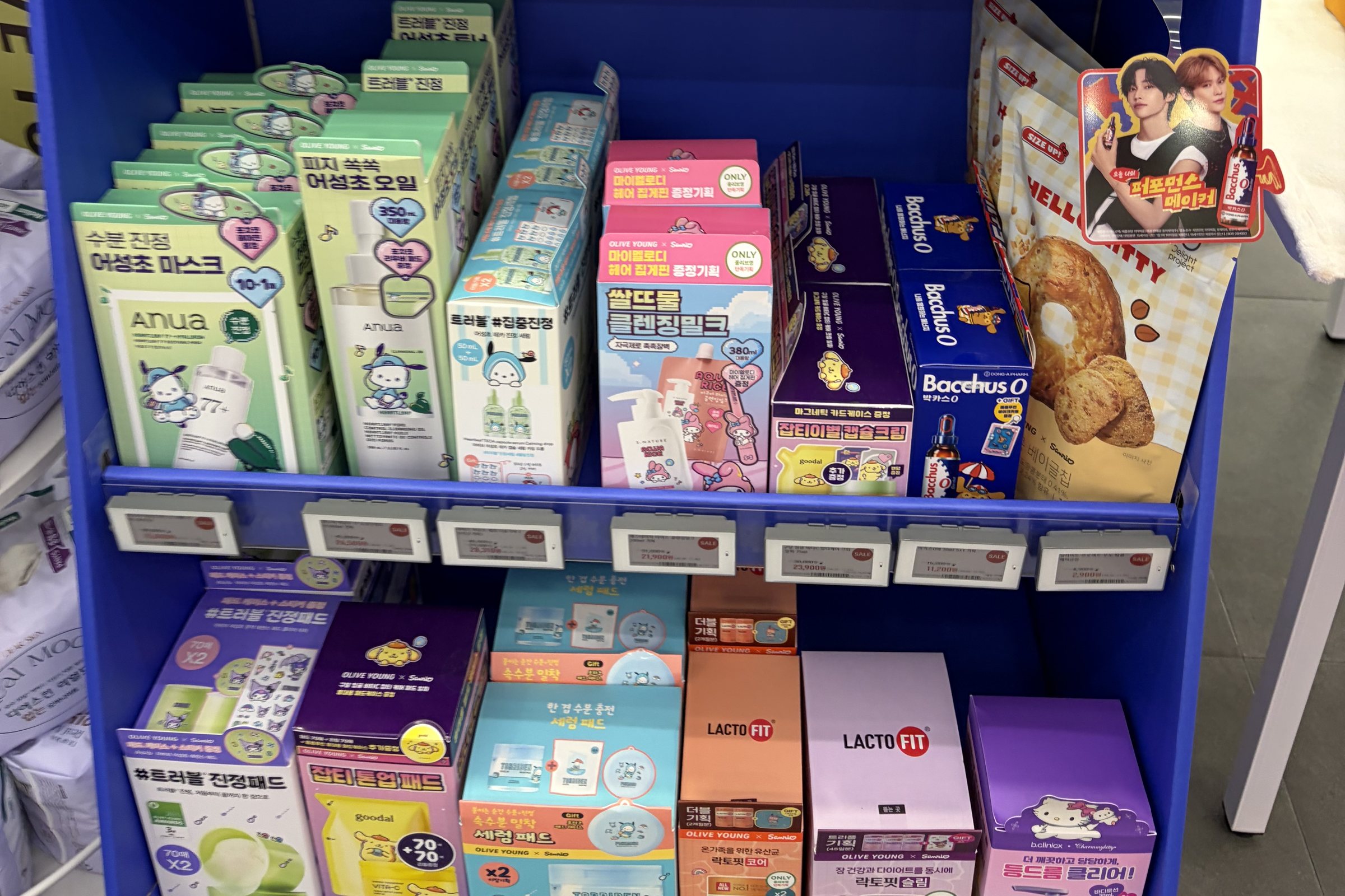 Lower shelf of the Olive Young Sanrio endcap with Anua heartleaf Pochacco sets, S.NATURE My Melody cleansing milk, Goodal capsule cream and Bacchus-O