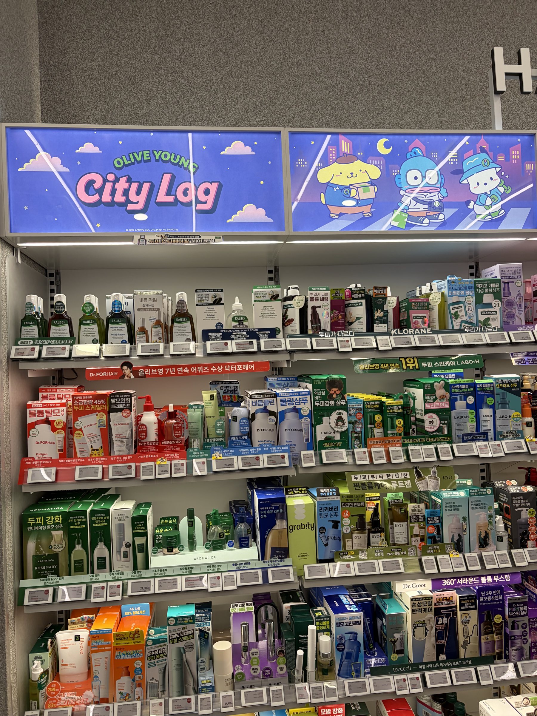 Olive Young skincare wall with Sanrio City Log banners showing Pompompurin, Hangyodon and Pochacco above the shelves