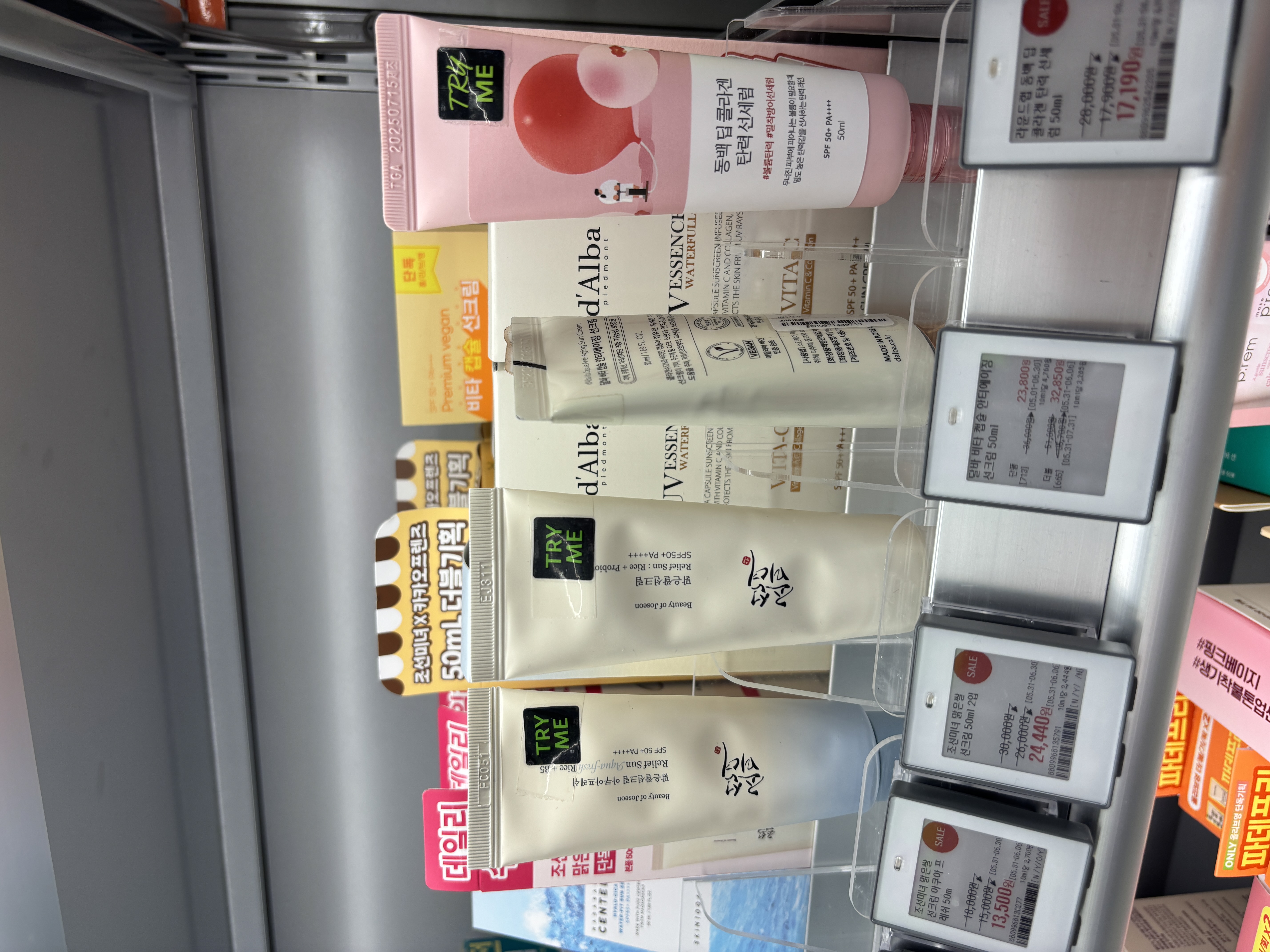 Beauty of Joseon Relief Sun products on Olive Young shelf showing Rice plus Probiotics and Aqua-Fresh Rice plus Aloe variants with TRY ME testers alongside d'Alba UV Essence products